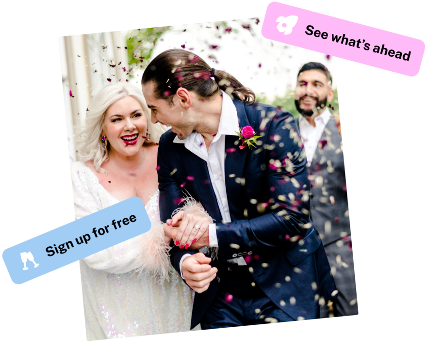 A happy couple holding hands as they’re showered with rose petals.